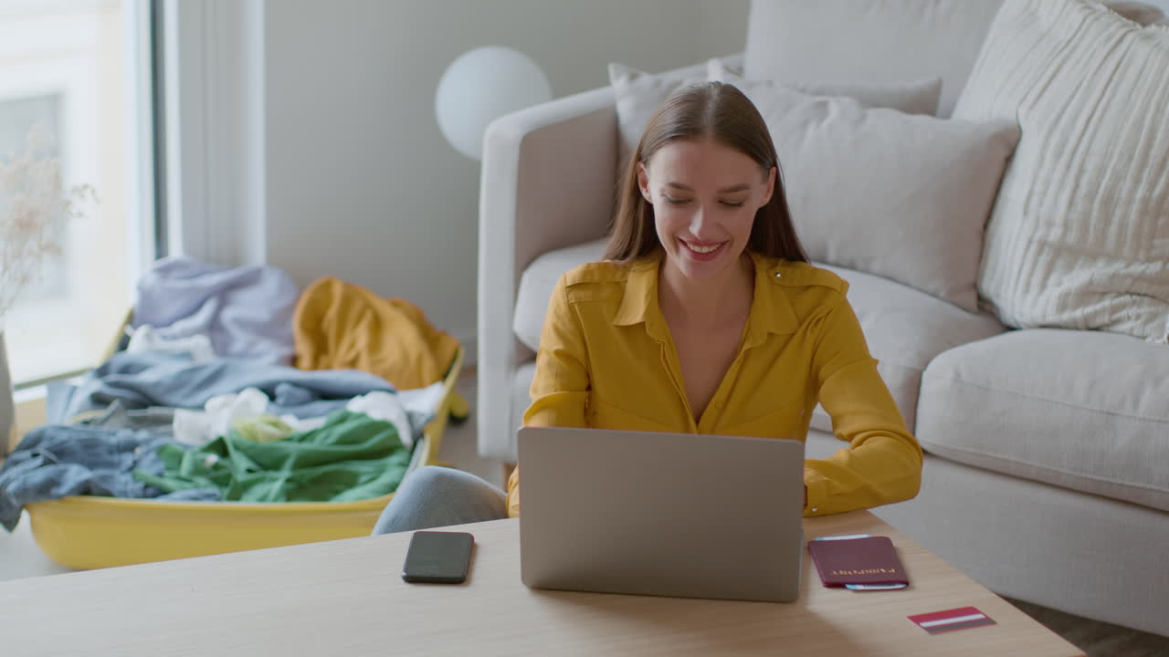 Woman working on laptop while preparing for a trip