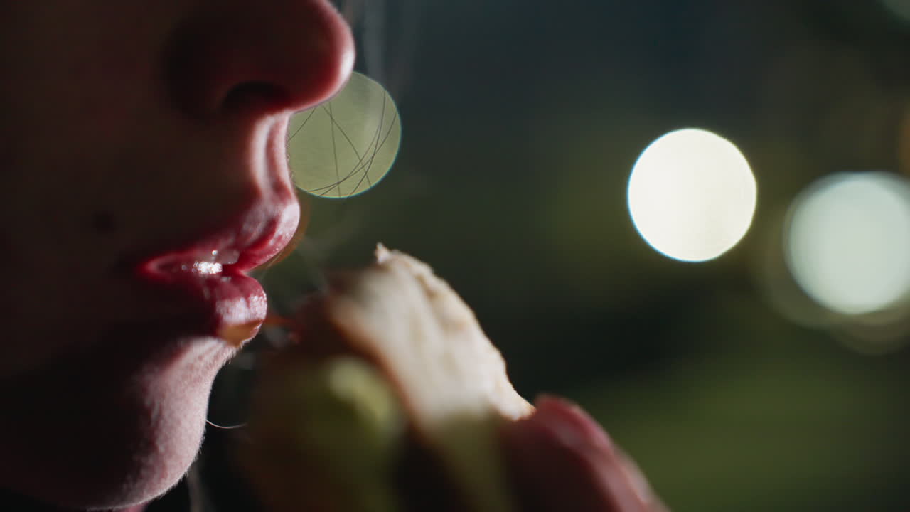 Wellness advocate enjoying tossed bread with egg under blurred city lights at twilight while savoring nourishing meal after outdoor training session on bench in quiet urban park setting
