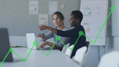 animation of green graph over diverse female coworkers discussing reports on laptop in office