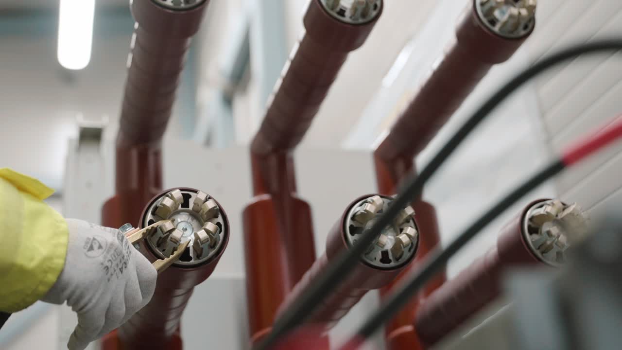 Worker inspects high voltage cables, focusing on safety and precision
