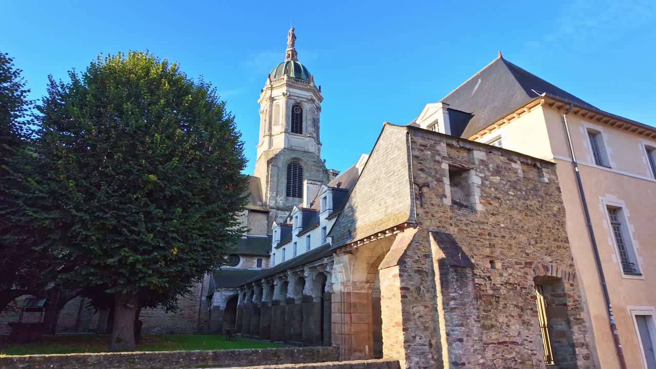 Church of Notre Dame Saint Melaine and surrounding buildings stand beneath soft daylight as trees frame the calm historic