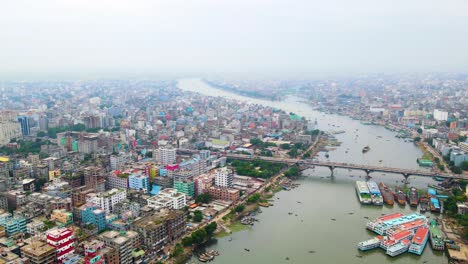 descending drone shot of dhaka, bangladesh with buildings and river with boat in buriganga