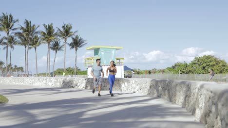 cheerful couple jogging on seafront