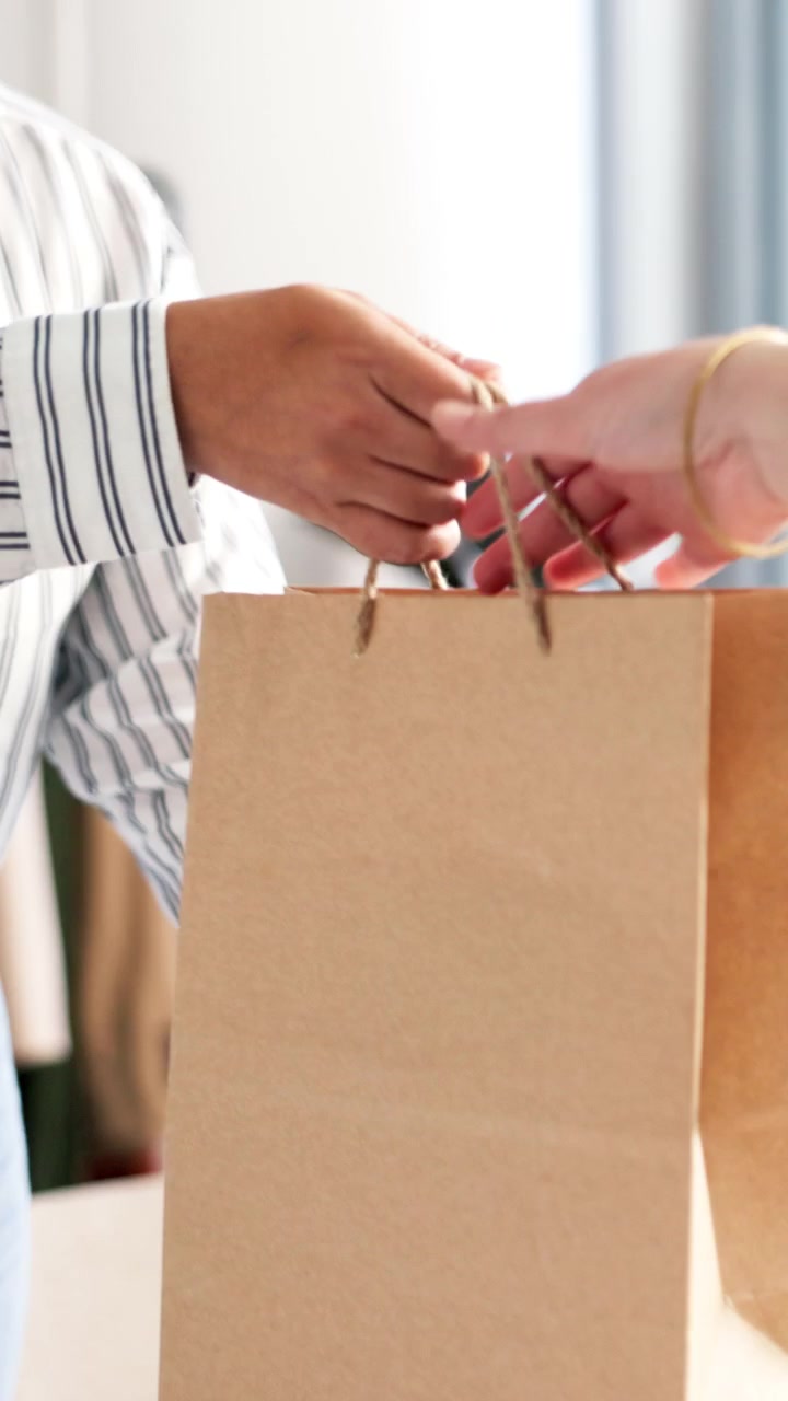 Shop Assistant Packing Item and Handing Paper Bag to Customer