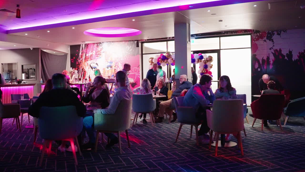 People Sitting And Socializing In Lounge Bar With Nightlife Flashing Party Lights, 4K Slow Motion