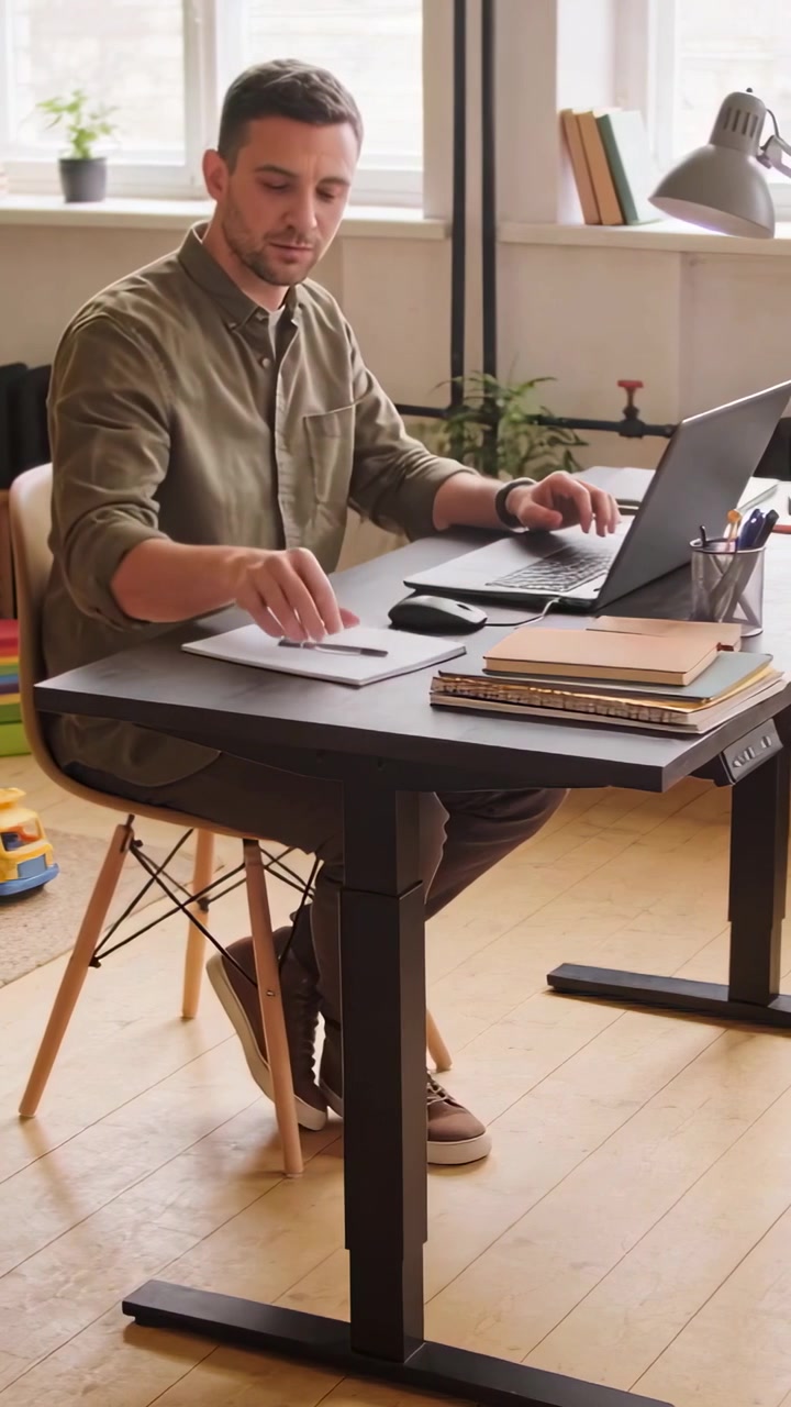 Video verticale: Uomo che digita con camicia color oliva, controlla un quaderno, torna al laptop, lavora da casa