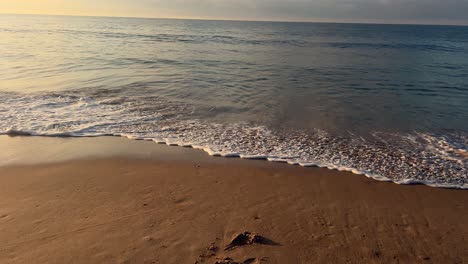 Paseando-Por-El-Mar-Mientras-Las-Suaves-Olas-Acarician-Las-Arenosas-Costas-Costeras,-Cubos-De-Concreto-Ubicados-En-La-Arena-Para-Protegerse-De-La-Erosión.