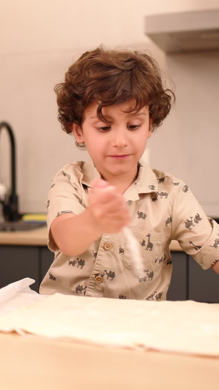 Bambino che cosparge farina sull'impasto in cucina