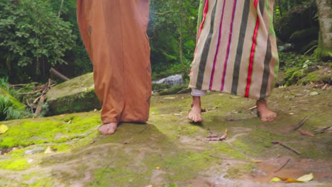 barefoot individuals in traditional attire dancing on mossy ground in oxapampa, peru, forest backdrop