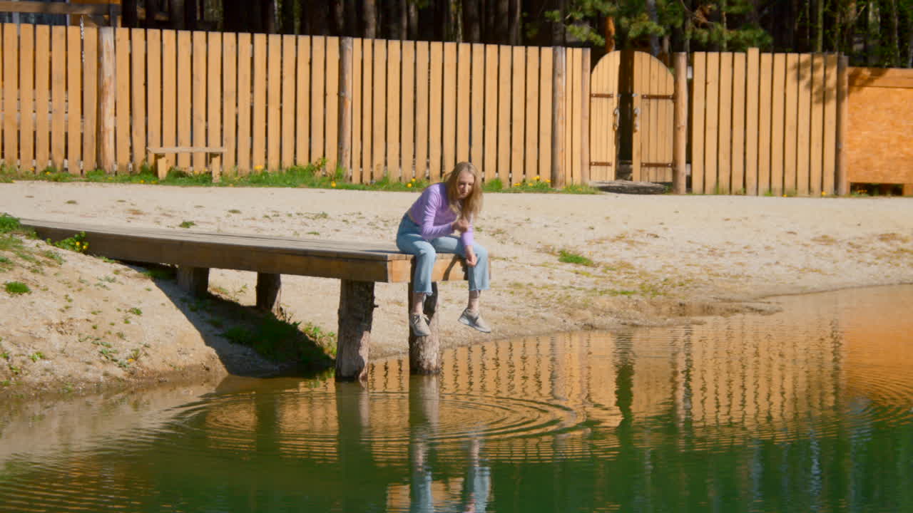 Woman sitting on a wooden dock by a lake