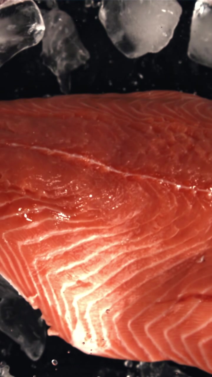 Schizzi d'acqua su filetto di salmone fresco e crudo e ghiaccio