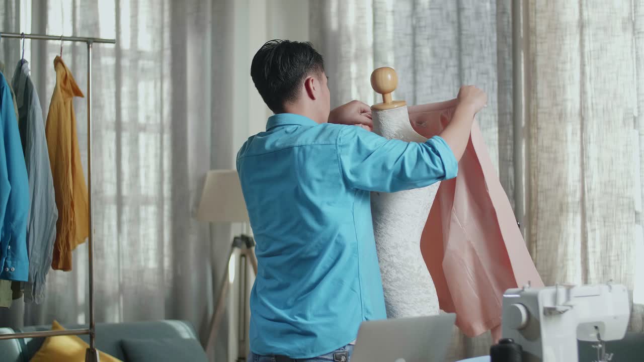스튜디오에서 옷을 디자인하는 동안 마네킨에 재을 입은 바느질 기계와 함께 아시아 남성 디자이너