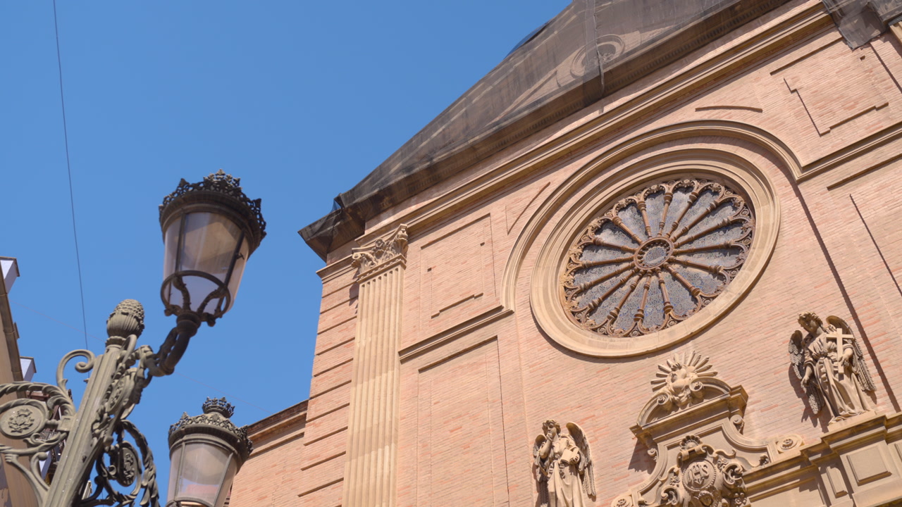 Baroque Cathedral Facade With Rose Window, Sunlit Terracotta Stone And Ornate Sculptures, Wroughtiron Lamp