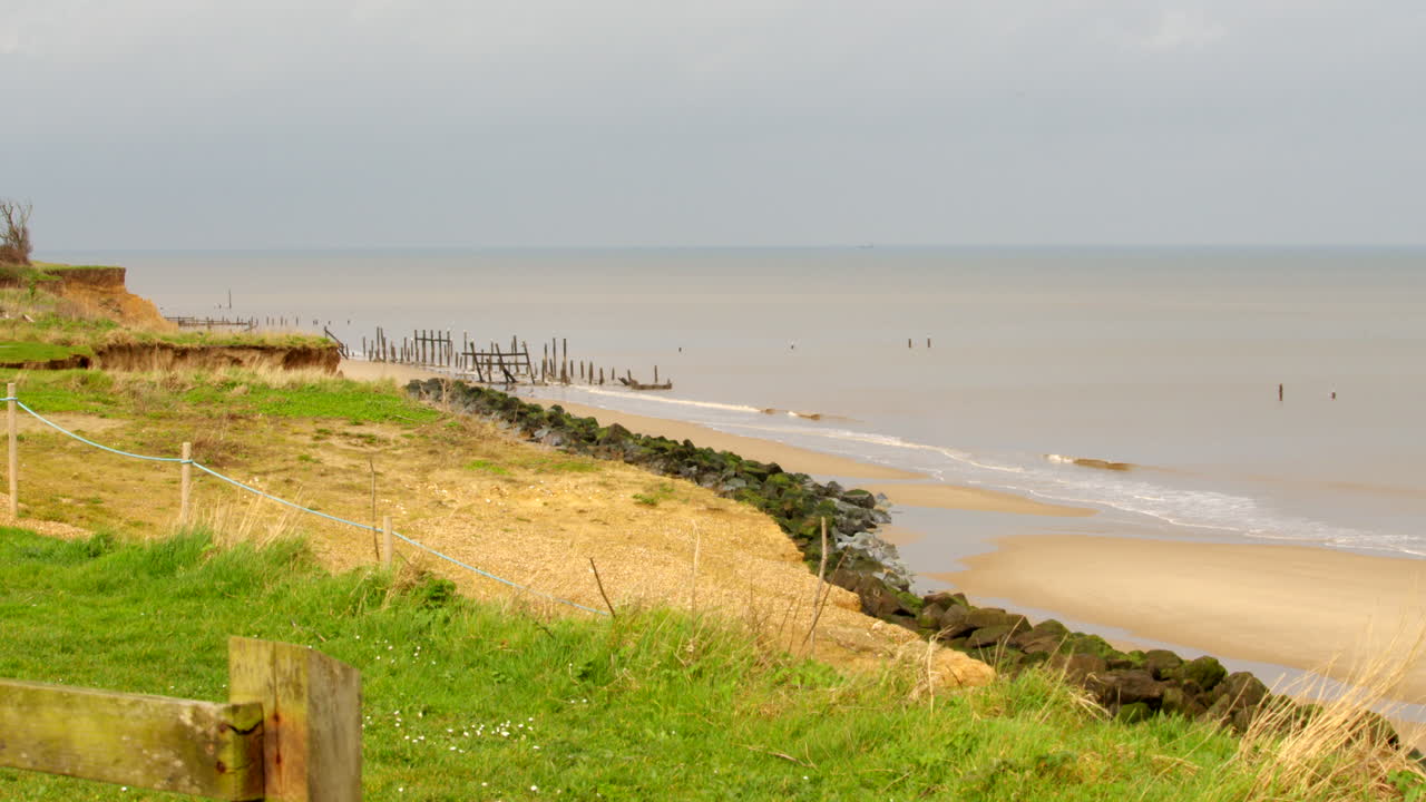 Inquadratura extra-ampia dell'erosione costiera e delle difese marittime abbandonate e fallite a Happisburgh a marzo 2024.