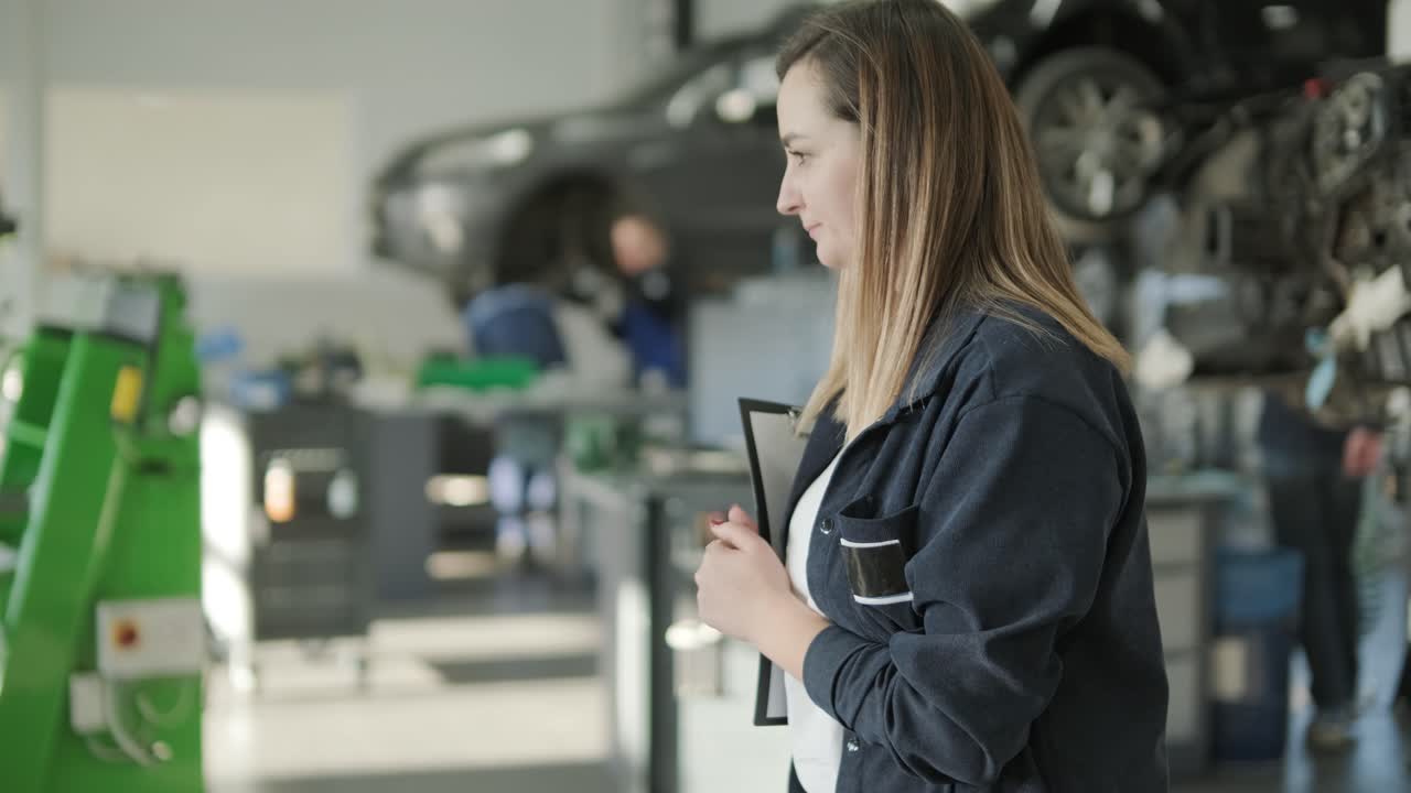 gerente femenina discutiendo la reparación de vehículos con el mecánico en el taller de reparación de automóviles