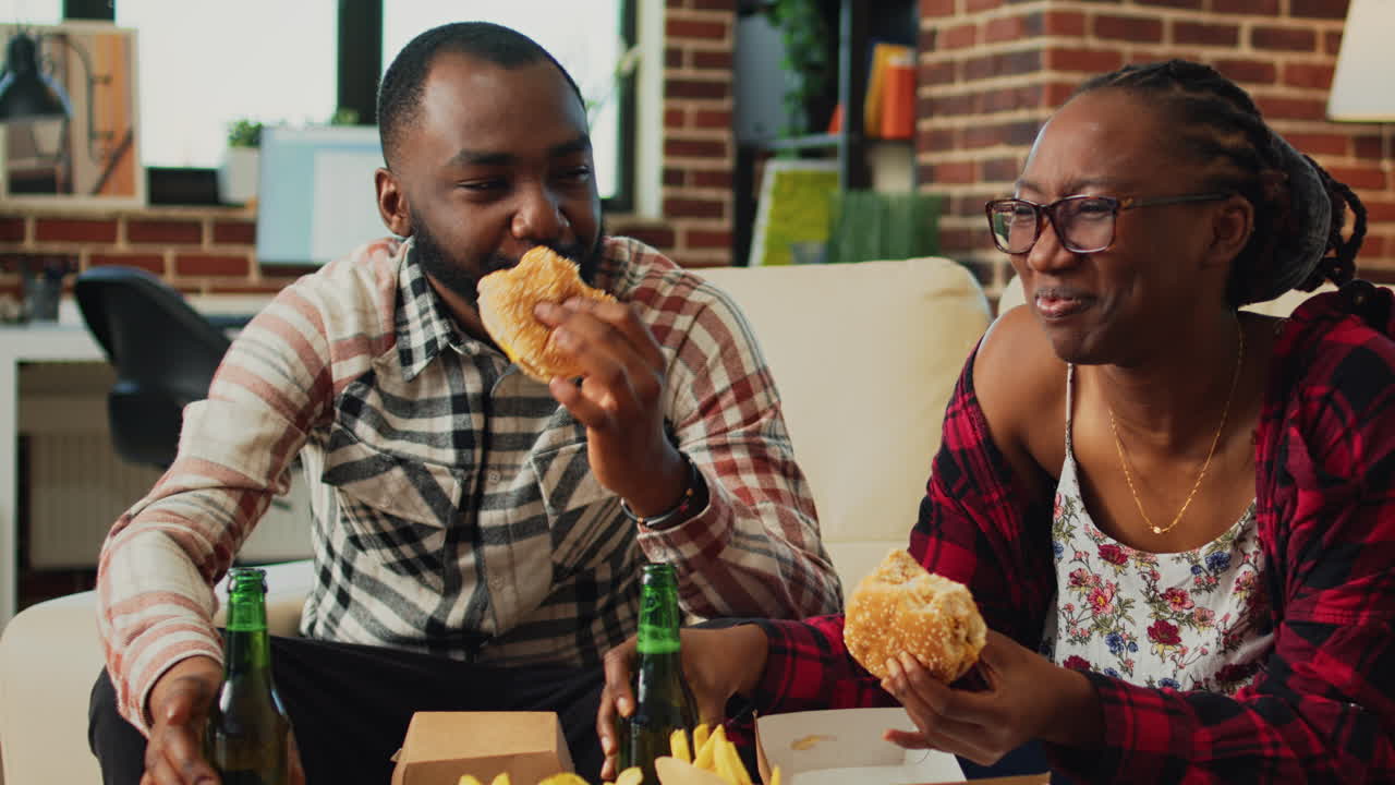 Modern life partners taking bite of cheeseburger