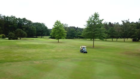 drone aerial high angle view shot of a golfer driving golf cart car on a golf course between forest trees