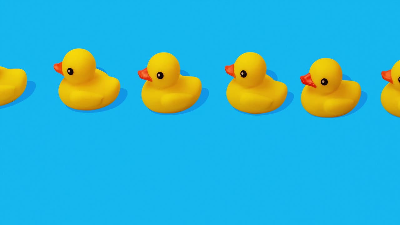 파란색 배경 정지 동작에서 가까운 줄에서 수영하는 노란색 고무 오리