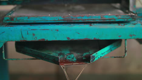 tilt down shot of a fruit compactor machine as coyol palm fruit oil pouring out