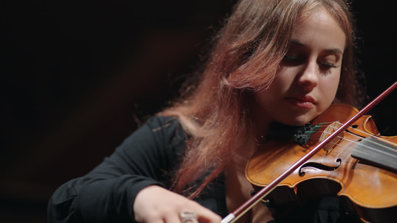una joven violinista está aprendiendo a tocar el violín o la viola en la sala filarmónica.