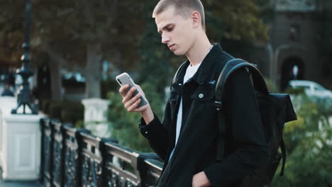 young student using mobile phone outdoors.