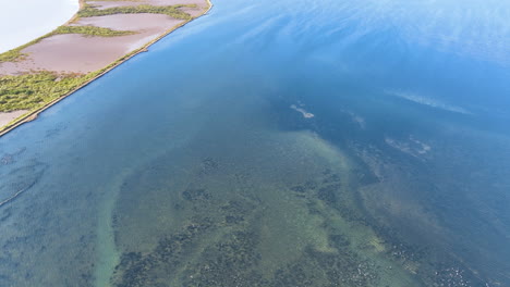 aerial hovers low over the unique underwater structures formed by salt pans evaporating and the crystallisation of sodium chloride from sea water. bright blue and aqua waters in the sub tropics.
