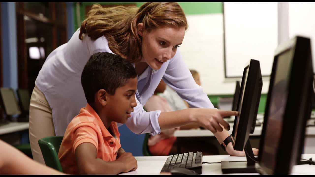 maestro ayudando a los niños de la escuela en la computadora personal en el aula