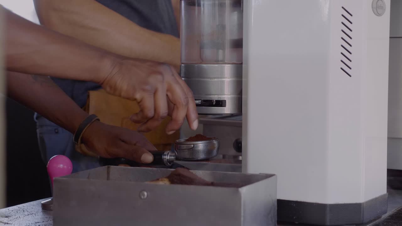 African barista cleaning coffe machine and making freshly brewed coffee at a street food market in Hermanus in South Africa.