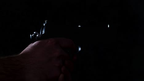 shoot slowly firing a pistol in a dark room until it is empty