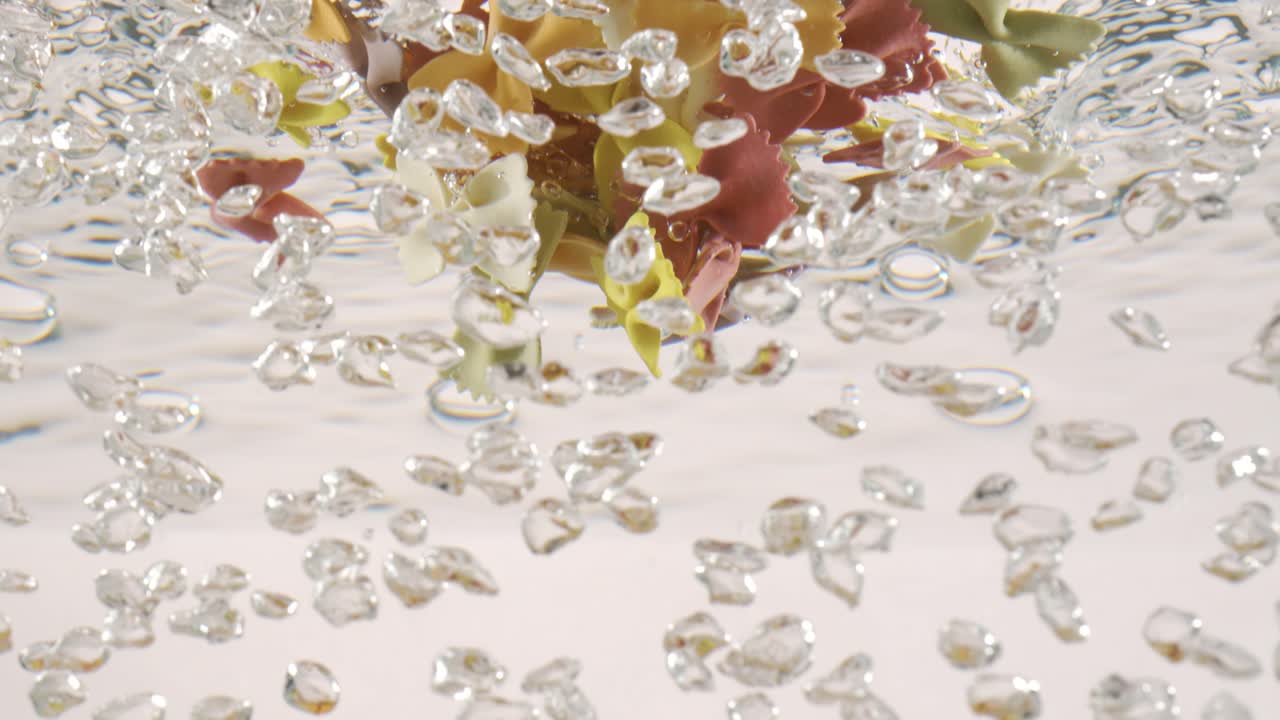 farfalle pasta tricolore en agua hirviendo. filmado con una cámara súper lenta de 1000 fps.