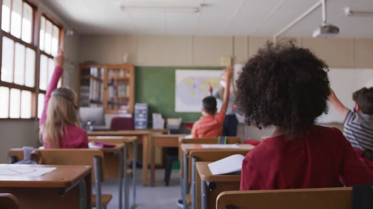 Grupo de crianças usando máscaras levantando as mãos na aula na escola.