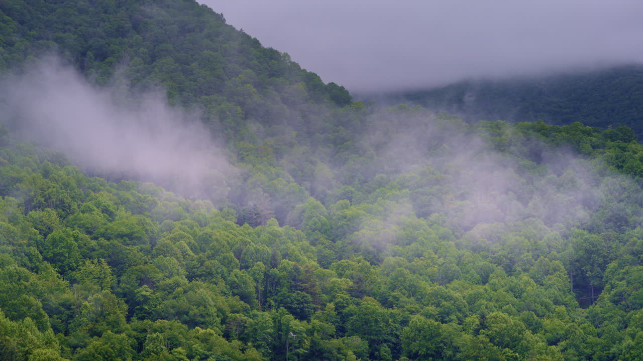 Drone footage floating past a peaceful Smoky Mountain valley cloaked in haze