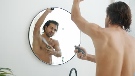 man applying deodorant in front of mirror