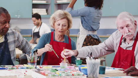 group of retired seniors attending art class in community centre with teacher