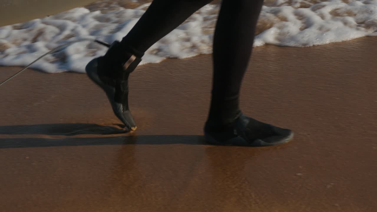 Surfer man walking to the beach at sunset preparing for surfing training and search for waves in Barcelona, spain, water, ocean exercise in sea with board, athletic male holiday or travel in vacation