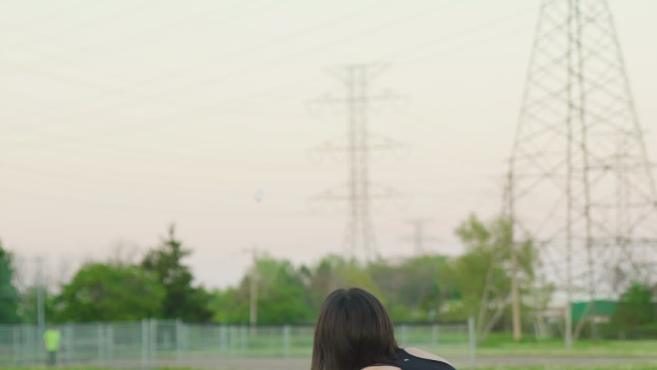 여자는 셔틀콕을 공중에 던진 다음 배드민턴 라켓으로 오버핸드로 제공합니다.