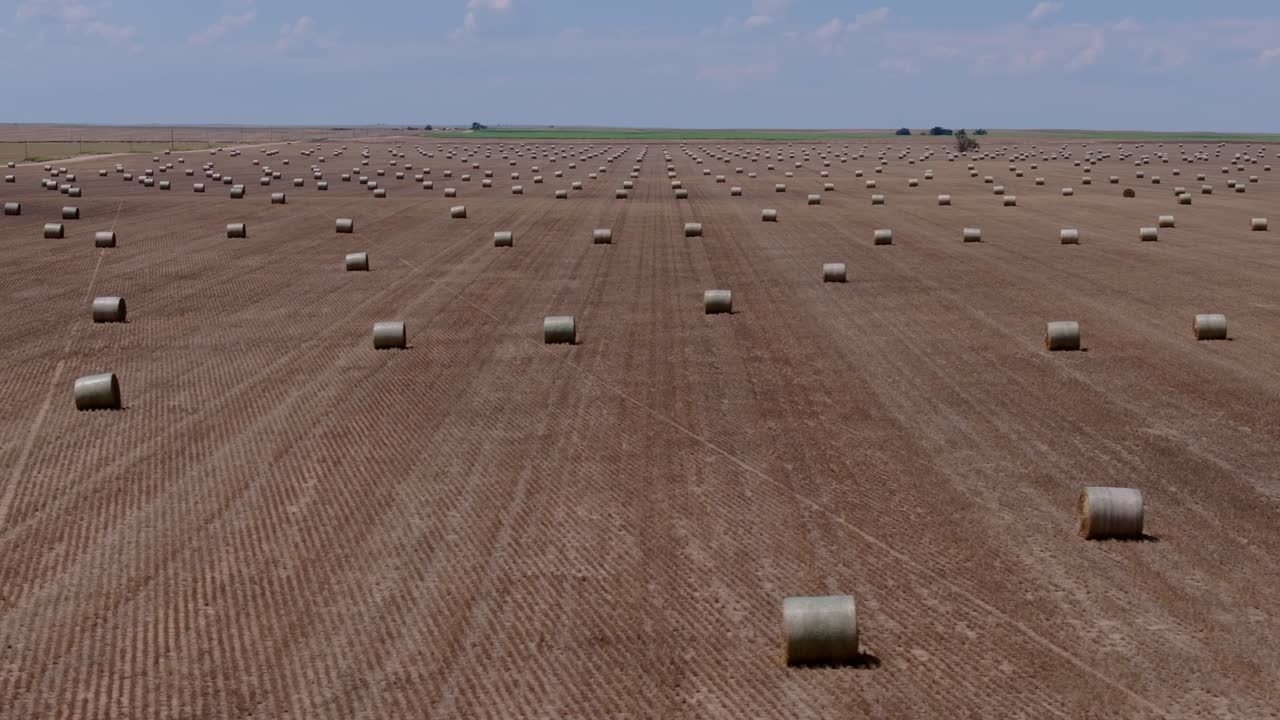 Aerial establishing evenly spaced hay bales across harvested Kansas field, agriculture perfect rows and tracks