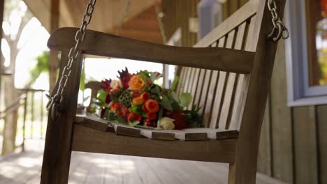 bouquet sitting on wooden rocking bench on porch