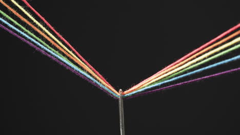 video de micro de hilos de color arco iris que pasan a través de la aguja con espacio de copia en fondo negro