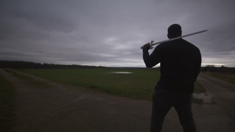 Modern-Black-Swordsman-Warrior-Awaiting-Battle-Opponent-in-Open-Field-Under-Red-Sky,-Europe,-4K-|-Muscular,-Intimidating,-Shadow,-Figure,-Blurry,-Dark-Clothes,-Powerful,-Patrol,-Guard