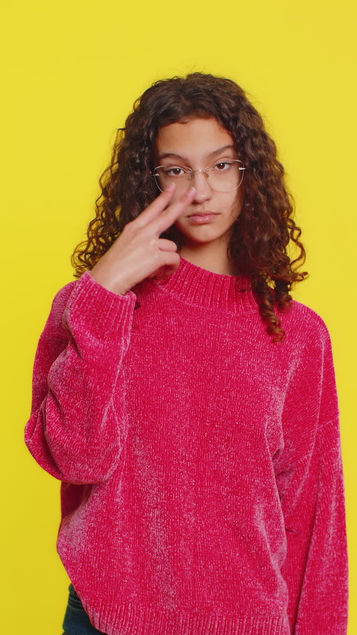 Young girl pointing at eyes and camera show i am watching you gesture spying watching on someone