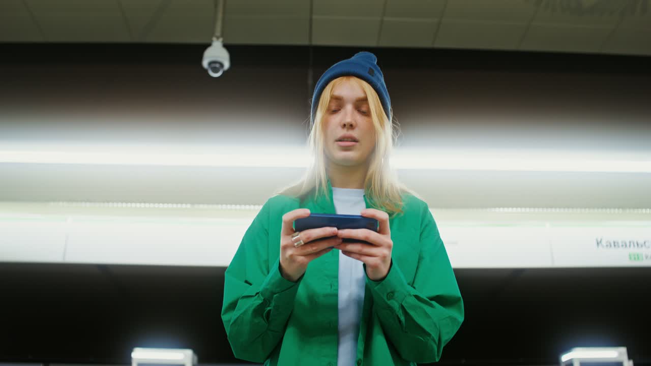 Woman playing game on phone at metro station