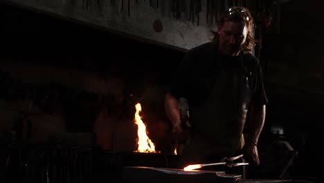 herrero trabajando en una barra de hierro