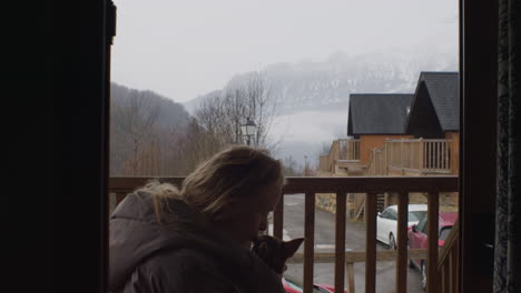 woman with dog by cabin on mountain vacation