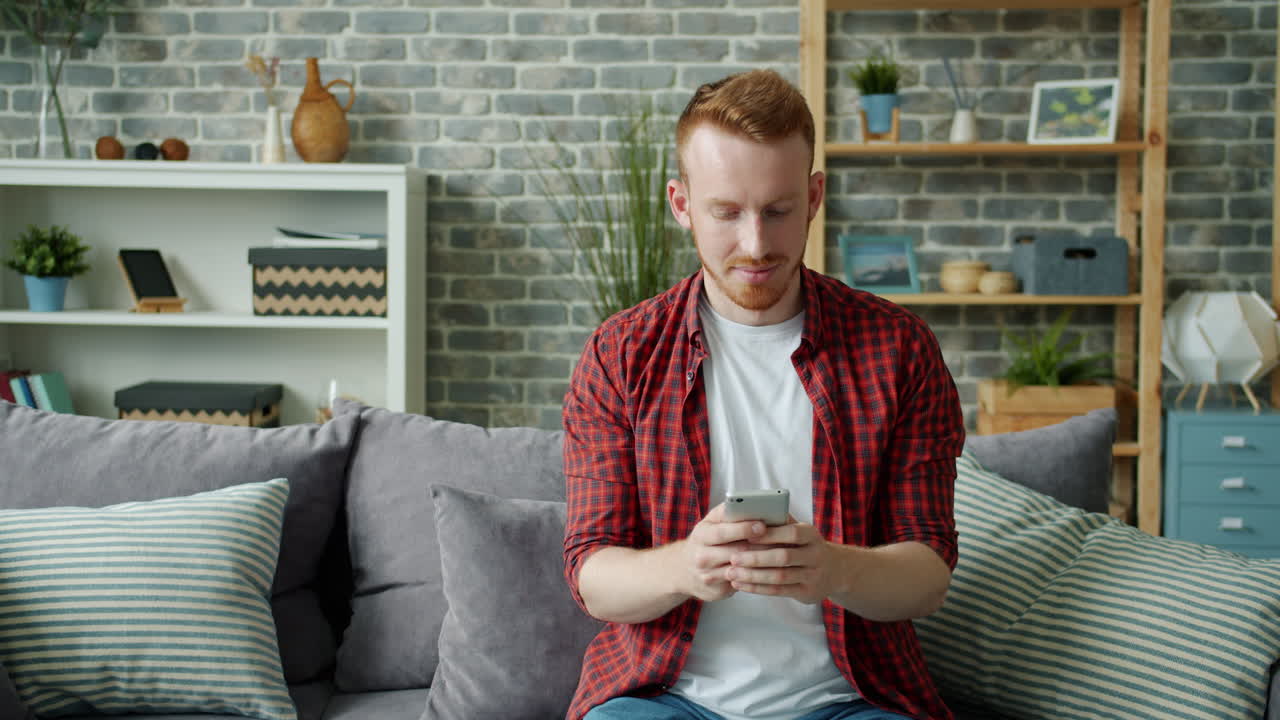 소파에서 스마트폰을 사용하는 남자