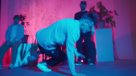 stylish male dancer moves to music in a smoky room with neon lighting.
