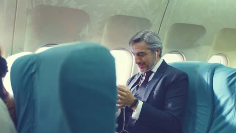 caucasian business man in formal suit put on earphones, enjoy listening to music in business class on airplane. the man feeling relax and happy, enjoying holiday travel trip by aeroplan transportation