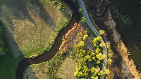 el tranquilo río marrón fluye a través del campo serpenteando y serpenteando junto al camino de tierra