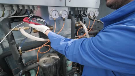 the technician checking power lines of the heat exchanger with current clamps