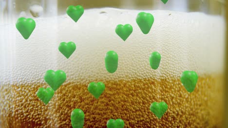 animation of st patrick's day green hearts on glass with beer background